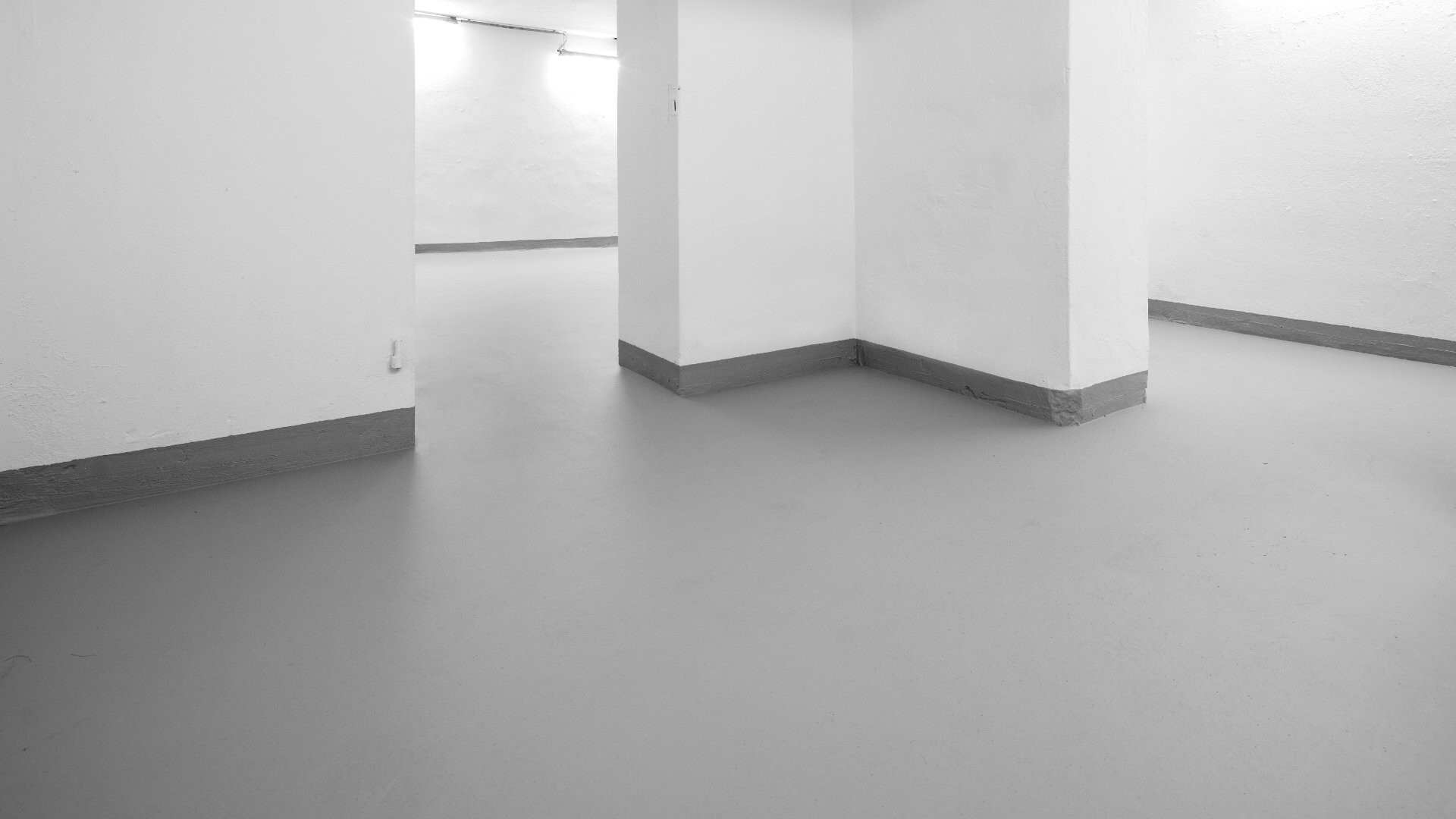 Aufnahme eines Kellers mit weißen Wänden und einem grauen Boden, der mit der Boden-Ausgleichsmasse ausgeglichen worden ist