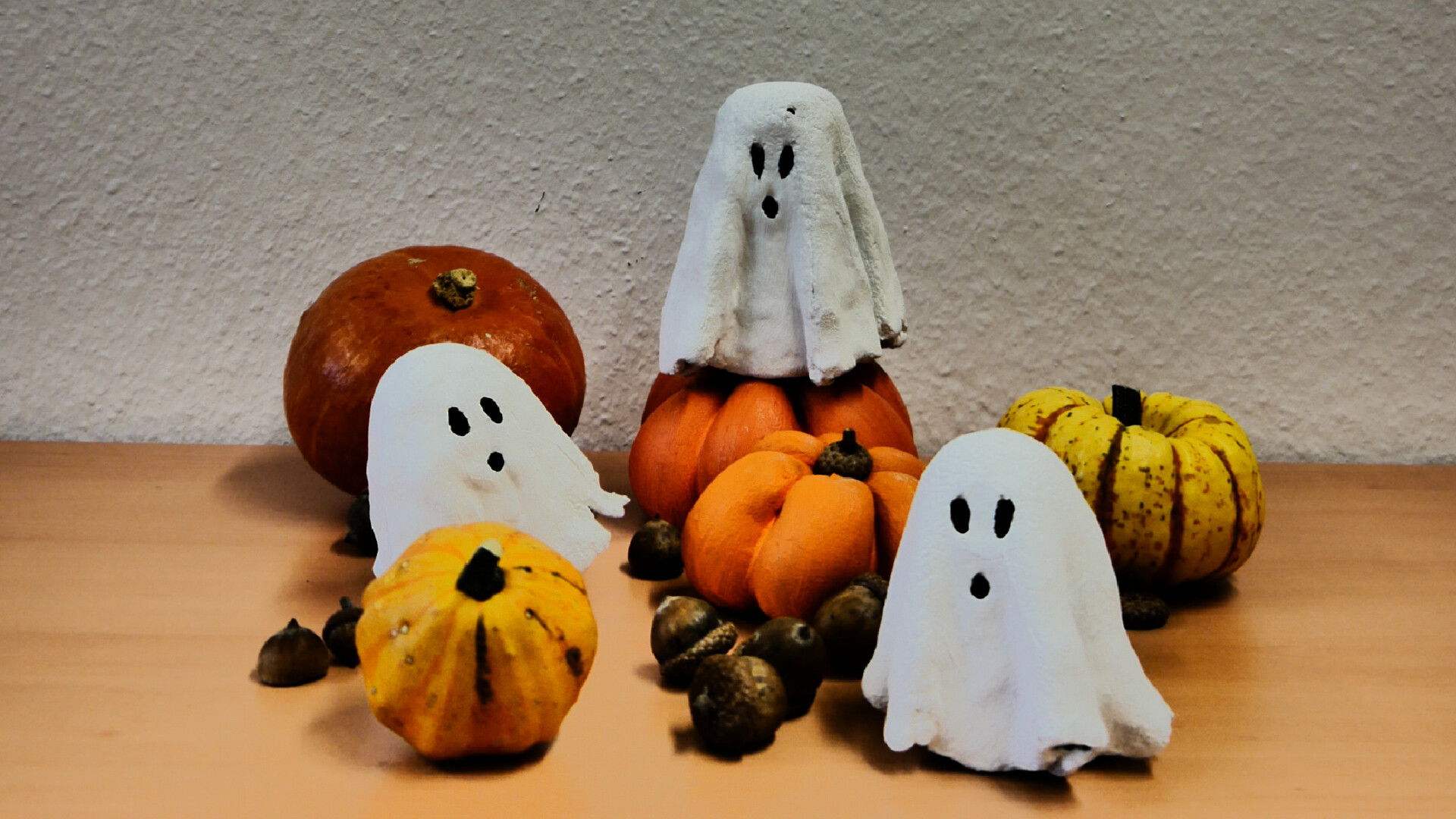 Aufnahme von Halloween-Deko bestehend aus drei Geistern aus Bastelbeton, Bastelbeton-Kürbissen und Zierkürbissen