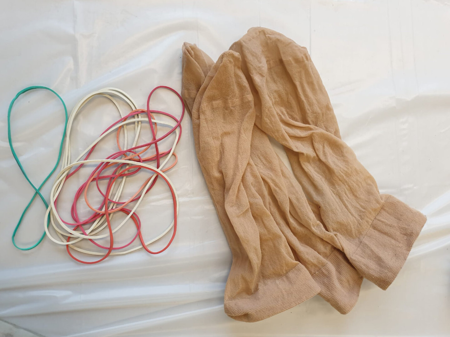 Aufnahme von Gummibändern und feinen Socken auf weißem Hintergrund. Dies ist das Material, mit dem Kürbisse aus Bastelbeton gebastelt werden