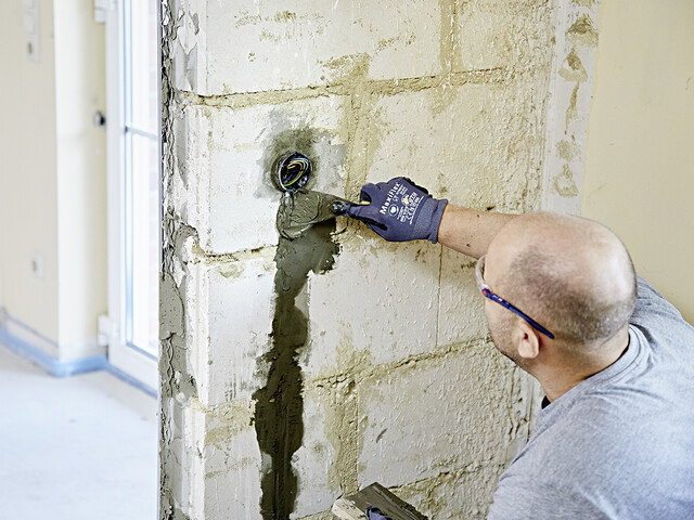 Aufnahme einer Person, die den Leitungsschlitz in der Wand mit Blitzzement verschließt