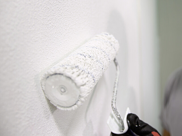 Nahaufnahme auf eine Malerrolle, mit welcher der Rollputz auf die Wand aufgerollt wird