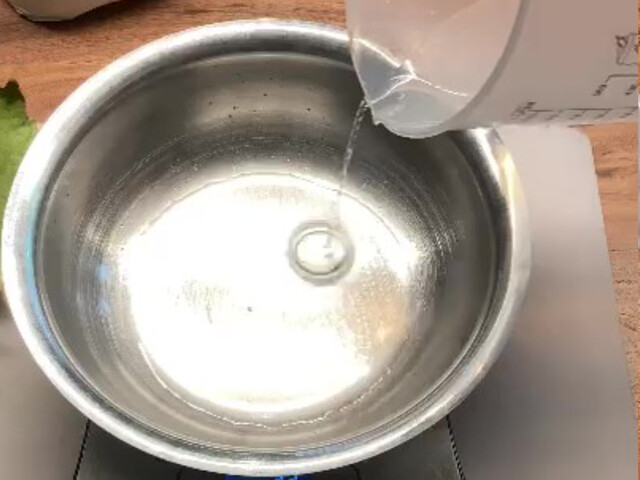 Nahaufnahme, wie Wasser aus einem Messbecher in eine Metallschale gegossen wird