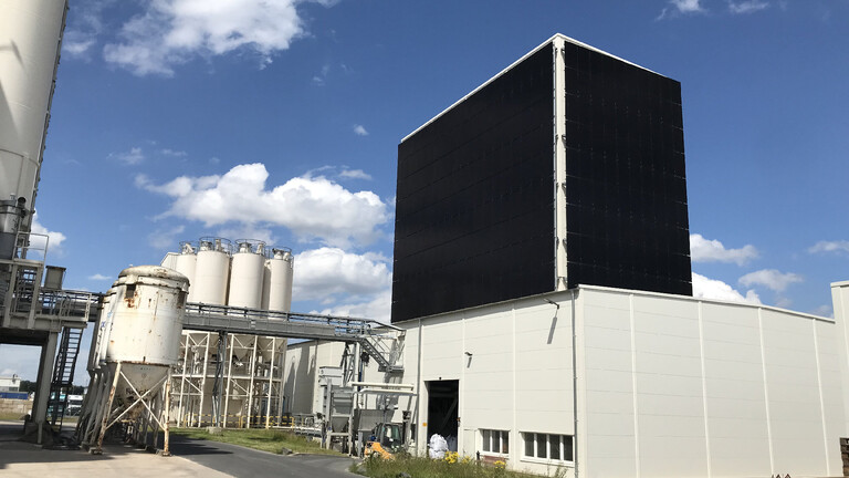 Aufnahme des Produktionsstandorts Weilerswist von Außen. Es sind Silos und ein Produktionsgebäude erkennbar. Am Turm des Produktionsgebäudes sind Solarpanele angebracht